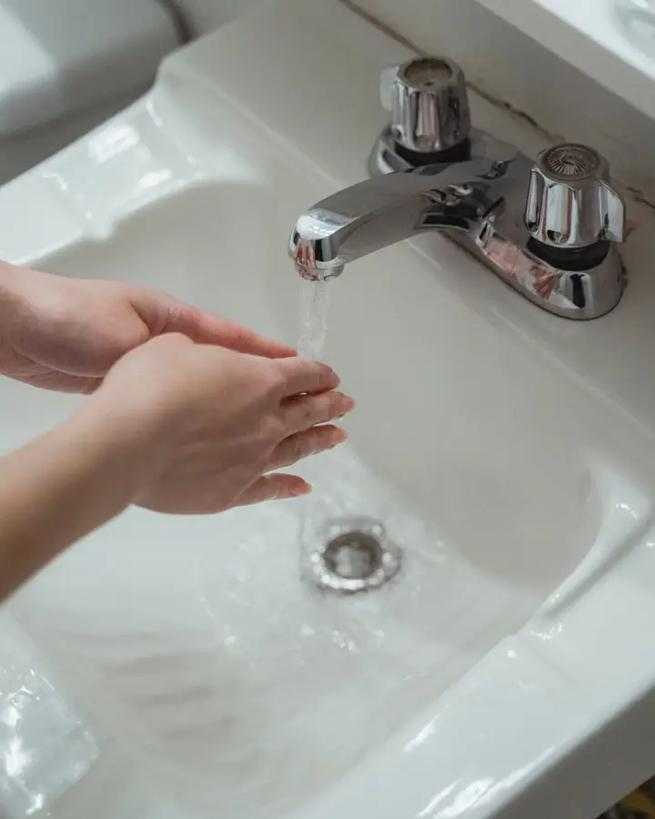 Clean water running from a kitchen faucet into a white sink