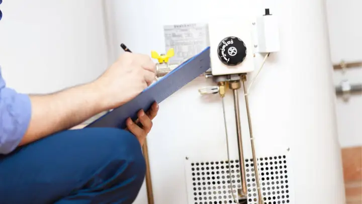 Plumber writing notes while inspecting a water heater